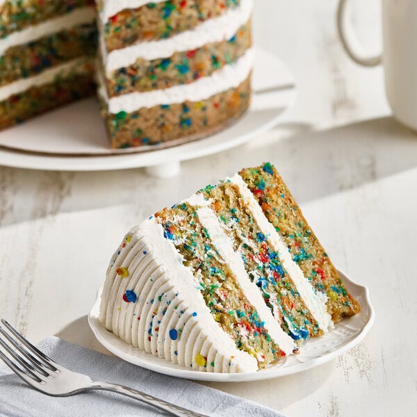 Slice of vegan Funfetti naked cake showing rainbow sprinkle-filled vanilla layers and frosting.